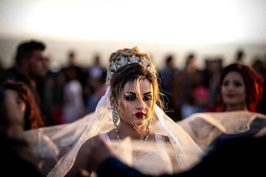 Amera, a young Yazidi bride dances following her marriage to Samir, a fellow Yazidi. The ceremony and after-party took place in a clearing outside of the Bajed Kandala Displacement Camp in Iraqi Kurdistan; all of those in attendance, as well as the bride and groom, were forced to flee their home of Sinjar, Iraq following an ISIS attack in August 2014. Currently home to over 9,000 displaced Yazidis, those living in the Bajed Kandala camp do their best to live life "normally", celebrating weddings, birthdays and religious holidays as they are able. This image was taken on December 29, 2018.