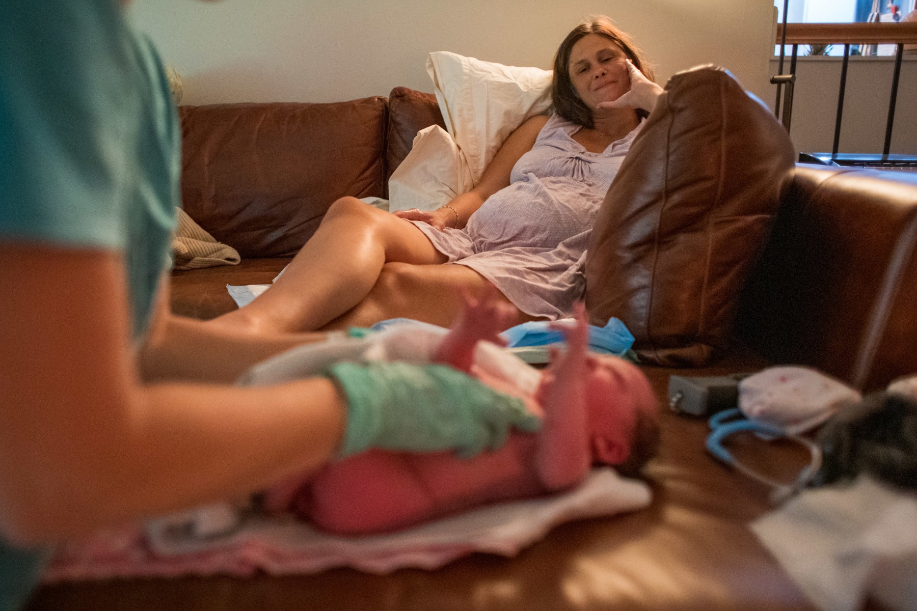 12:30am - After cleaning up and changing into fresh clothes, Kate looks at June while Lauren conducts a newborn exam. During the exam, Lauren checks her overall appearance and skin for common birth defects, as well as record her vitals and measurements.