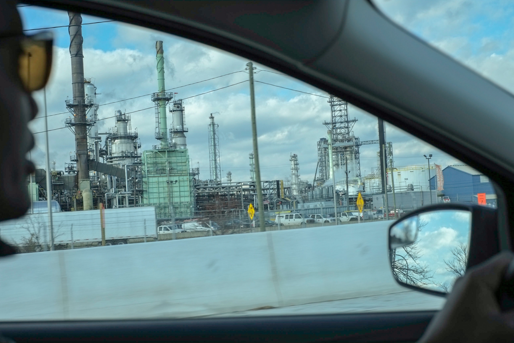 Mamba looks out his car window at the Marathon Oil Refinery in southwest Detroit. After working factory jobs when he first arrived in the US, Mamba felt that his education and successes in Burundi did not translate in America. "I hate to say it," he says "but because I did not speak English and I came from Africa, they did not trust that I was capable of the job. I learned English in 6 months. I have proven I am smart, and I can learn the job in just two or three months."